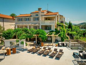 a large house with lounge chairs and a patio at Beach Suite Nina in Rab