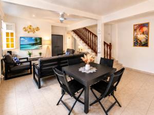 a dining room and living room with a black table and chairs at Villa Coralys - Plage - Cozy in Schœlcher +10 photos