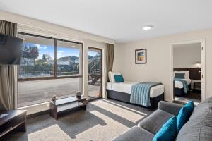 a living room with a couch and a bed and a window at Ashford Motor Lodge in Christchurch