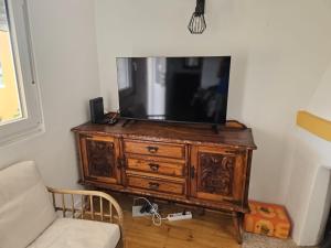 a tv sitting on top of a wooden dresser at Relaxing Riverside Escape & Stunning Sunset Views in Santa Comba Dão