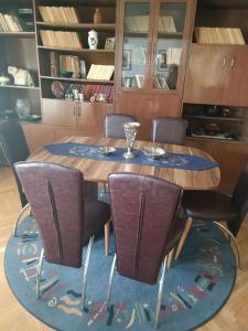 a dining room table with chairs and a blue rug at Apartman Kali Leskovac in Leskovac
