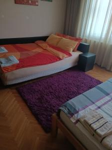 a bed with a purple rug next to a window at Apartman Kali Leskovac in Leskovac