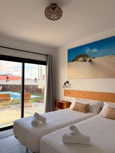 two beds in a room with a view of the beach at Casa El Cachorro in La Oliva +22 photos