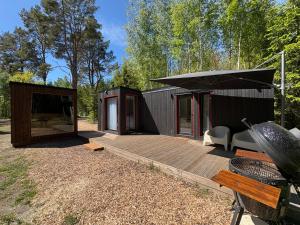 a small cabin with a deck and a black umbrella at MetsaMaja in Hiiumaa