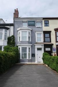a grey house with a white door and a driveway at The Meridian in Southport