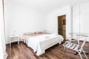 a white bedroom with a bed and a glass table at Guesthouse Tuta in Pakoštane