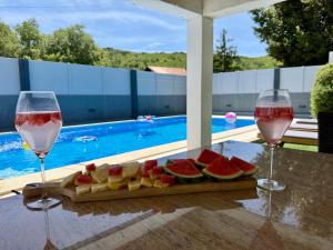 two glasses of wine and a cutting board with fruit at Kameni dvori - Family Villa with Pool & Jacuzzi for 8 in Imotski