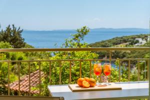 a table with two glasses and oranges on a balcony at Amorosa Nest - Adults Only by Eutopia in Syvota