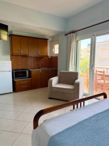 a room with a bed and a chair and a kitchen at Mihasi Apartments in Ksamil