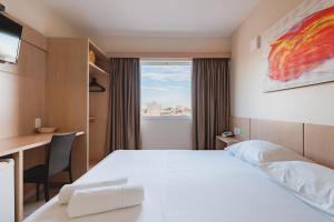 a hotel room with a bed and a desk and a window at Savana Hotel in Uberlândia +37 photos