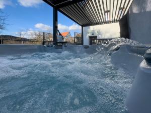 a jacuzzi tub with snow on the ground at Veloralux Apartman in Kovácsszénája