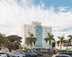 a large building with cars parked in a parking lot at Savana Hotel in Uberlândia
