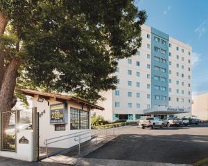 a building with a tree in front of a street at Savana Hotel in Uberlândia