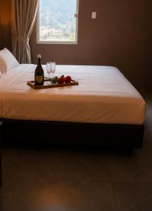 a bed with two glasses of wine and a tray of flowers at Aconchego Valença & Spa in Nova Friburgo