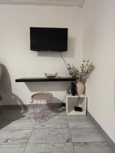 a room with a tv on a wall with a stool at Studio agréable et paisible in Aubagne