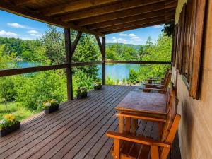 a wooden deck with benches and a view of a lake at Lake View Glamping pod Radyní bez tekoucí vody s omezenou elektřinou in Hvížďalka