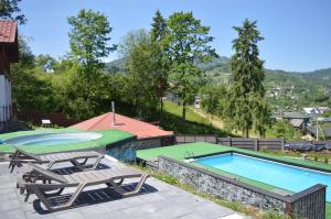 a swimming pool with two chaise lounges next to at Котедж Villagoria з теплим басейном in Slavske