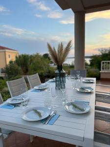a white table with plates and wine glasses on it at Four bedroom Beach House Amaya Medulin in Medulin