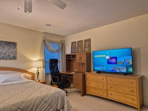 a bedroom with a bed and a desk with a television at Meadowridge Haven in Maple Ridge