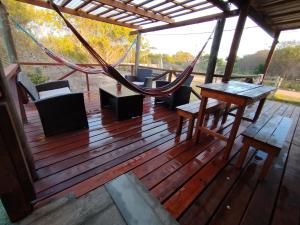 a wooden deck with a hammock and a table and chairs at casa Andylu in Punta Del Diablo