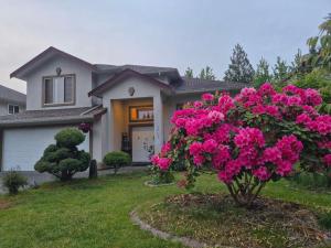 a house with pink flowers in front of a house at Meadowridge Haven in Maple Ridge