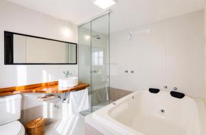 a white bathroom with a tub and a glass shower at Refúgio nas Nuvens Ninho das Águias in Nova Petrópolis