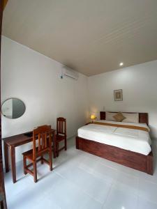 a bedroom with a bed and a desk and a table at Pondok tulamben in Karangasem
