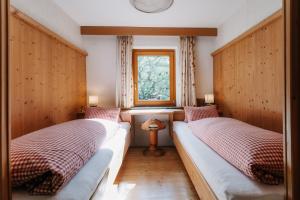 two beds in a room with a window at Weifer Biobauernhof in Prägraten