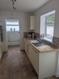 a kitchen with white cabinets and a sink at Grange Retreat in Pontnewydd +15 photos