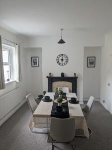 a dining room with a table and chairs and a clock at Grange Retreat in Pontnewydd