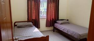 two beds in a room with a window at Impian Melaka Homestay in Malacca