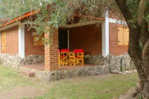 a house with a porch with red chairs on it at Lo de Chimila in San Javier