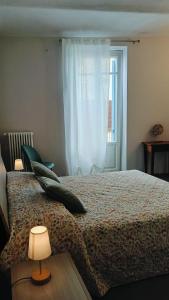 a bedroom with a bed with a lamp and a window at A casa di Anna in Cocconato