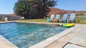 a person in a swimming pool with chairs and a dog at Lake House Boulaouane in Douar Annbirat