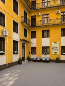 a yellow building with chairs in front of it at Esprit Residences Budapest in Budapest