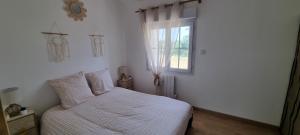 a white bedroom with a bed and a window at La Grange in Champagne-de-Blanzac