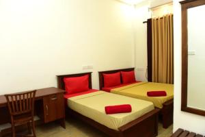 a room with two beds with red pillows and a desk at Royal Beach Hotel in Trincomalee +10 photos