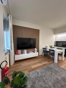 a living room with a table and a large television at Corona dei Sogni Appartamento moderno vicino Ospedale e Centro in Novara
