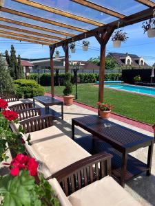 a patio with benches and a table and a pool at Pensiunea Tirol Baile Felix in Baile Felix