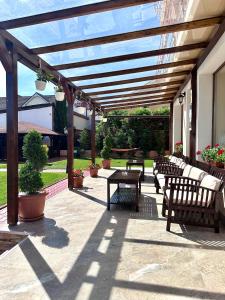 a wooden pergola with benches and tables on a patio at Pensiunea Tirol Baile Felix in Baile Felix +33 photos