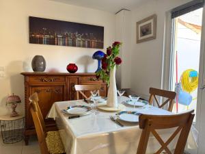 a dining room table with a white table cloth and a vase with flowers at Charmant T2 à 5 minutes de l'Aéroport d'Orly in Paray-Vieille-Poste