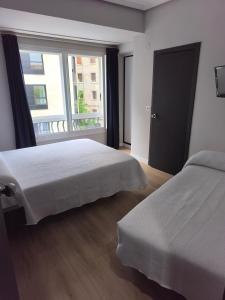 a bedroom with two beds and a large window at Hostal Cafetería La Rotonda in Ourense