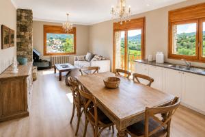a kitchen and living room with a table and chairs at CaL QuEROL Llivia 2 piscina, 8 pax, 2 baños y parking in Llivia