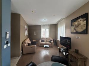 a living room with two chairs and a tv at Appartement Cuvier in Roubaix