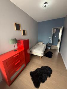 a bedroom with a bed and a red dresser and black rugs at Appartement Cuvier in Roubaix