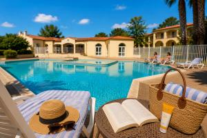 a table with a hat and a book next to a pool at Horizon Bleu Canet in Canet-en-Roussillon