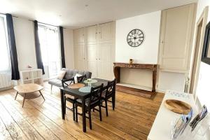 a living room with a table and chairs and a clock at Appartement Centre-ville Dole in Dole