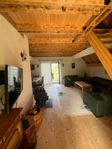 a living room with wooden ceilings and a flat screen tv at Peaceful Cottage in Bijelo Polje