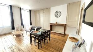 a living room with a table and chairs and a clock on the wall at Appartement Centre-ville Dole in Dole