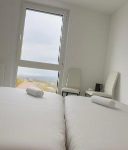 two beds in a room with a large window at ESER - Haus am Vogesenblick in Bad Bellingen